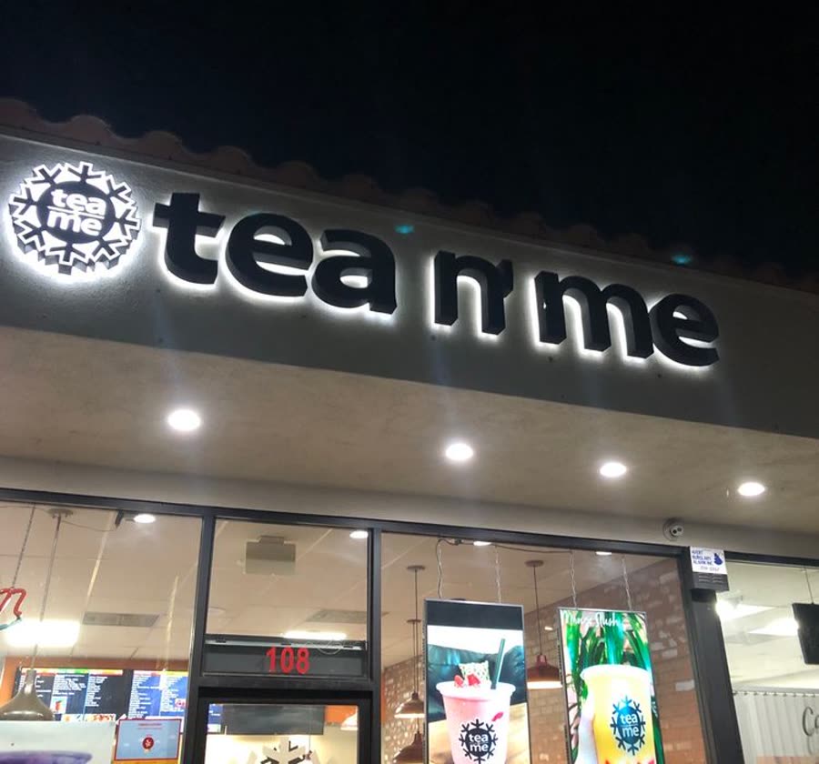 The lit tea n' me sign above the shop front at night