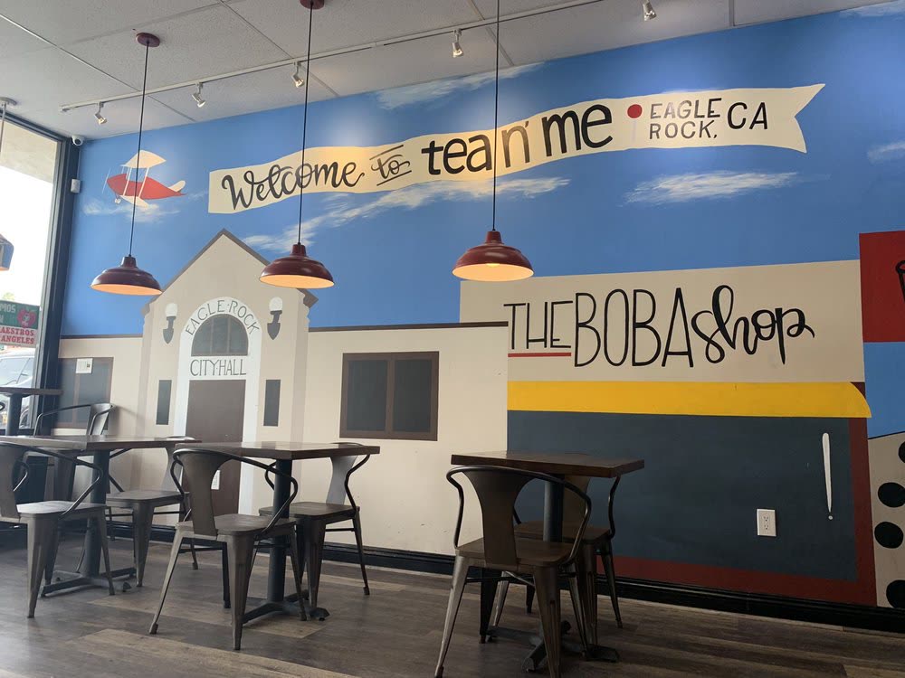 The painted wall inside the shop, with Eagle Rock City Hall, red pendant lamps and the hand-lettered welcome banner