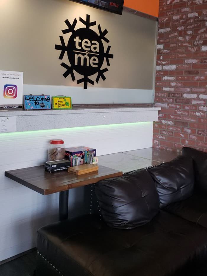 A small table and a couch seat beside the counter shelf and the brick wall