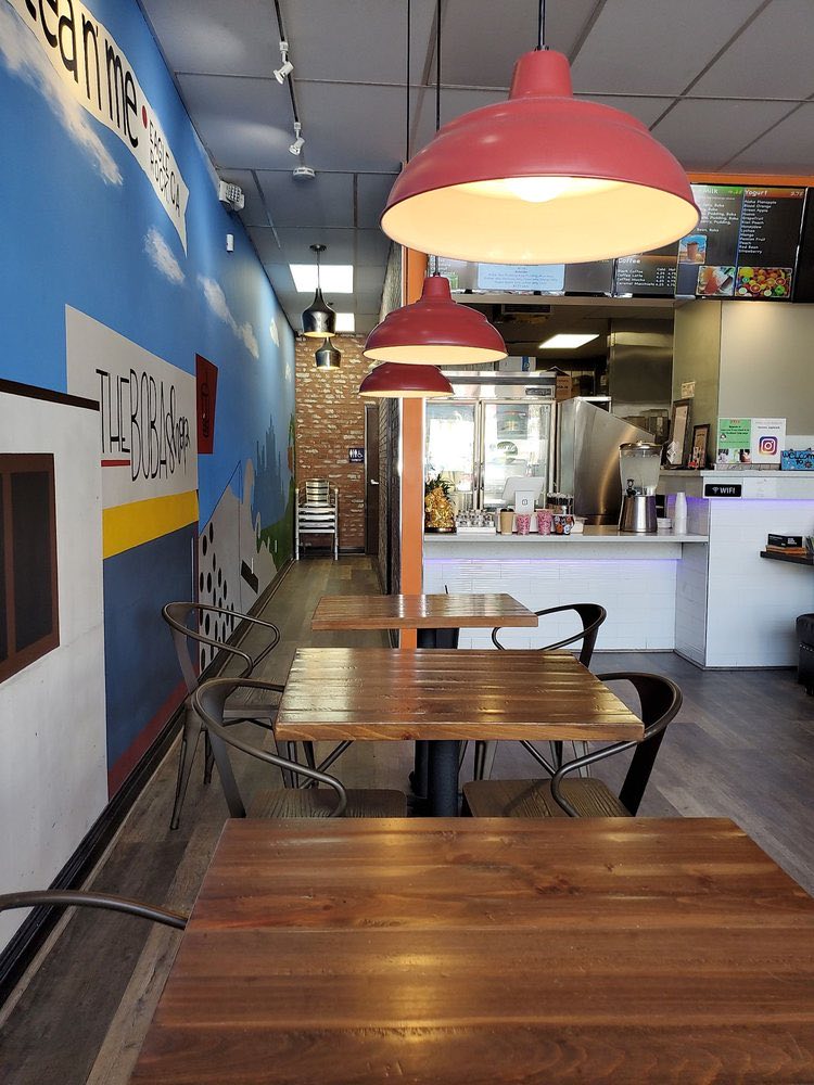 The seating area, with the hand-painted blue wall on the left, wooden tables under red pendant lamps, and the counter at the back.